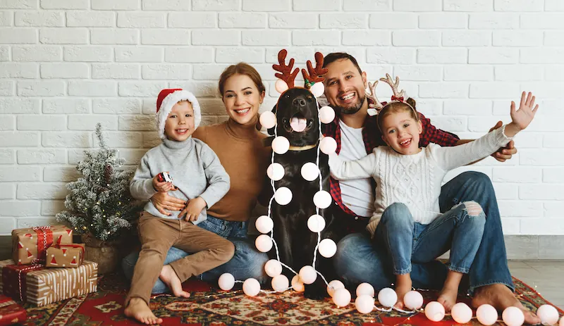 Family posing for picture with dog at christmas time