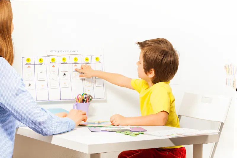 Child pointing to calendar at a table